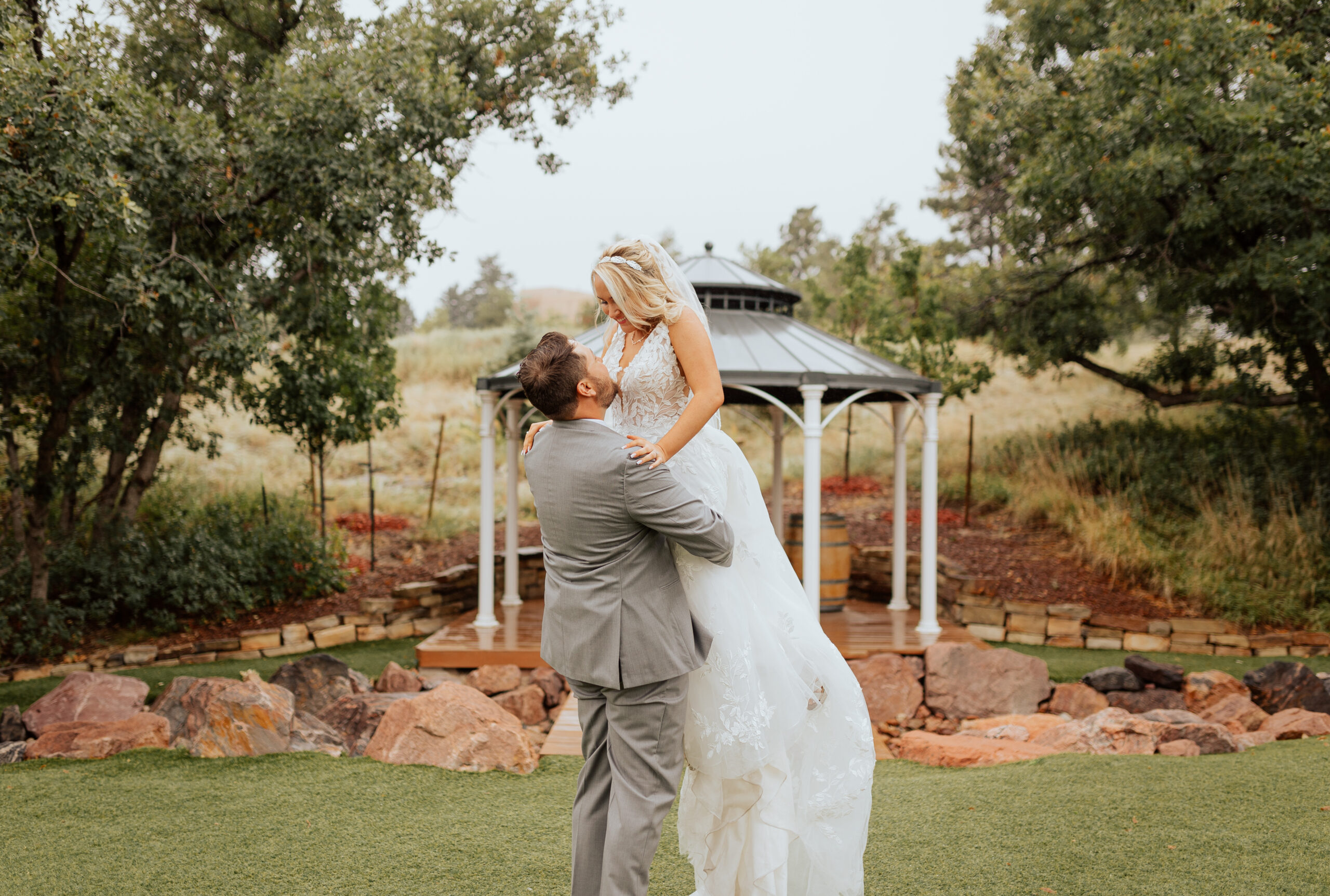 Bride and groom portrait at Creekside Event Center. The groom is holding the bride up and they are smiling at each other. Captured by Colorado wedding & elopement photographer, Michelle Betz Photography