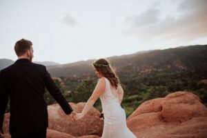 A couple holding hands and walking during their elopement. Surrounded by Garden of the Gods. Captured by Michelle Betz Photography