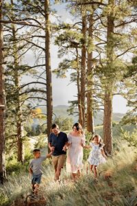 A family holding hands and walking through the forest. Michelle Betz Photography.