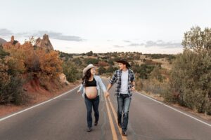 A couple running up the street together. Garden of the Gods background. Taken by Michelle, a Colorado Springs maternity photographer