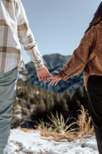 A detail photo of a couple touching hands. With mountains in the background. Captured by Denver engagement photographer, Michelle Betz.