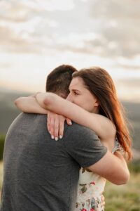 A couple hugging each other, looking off into. the distance. Captued by Michelle Betz Photography.