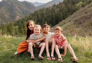 family photography Colorado Springs CO photo of 4 children in front of green grass and mountains