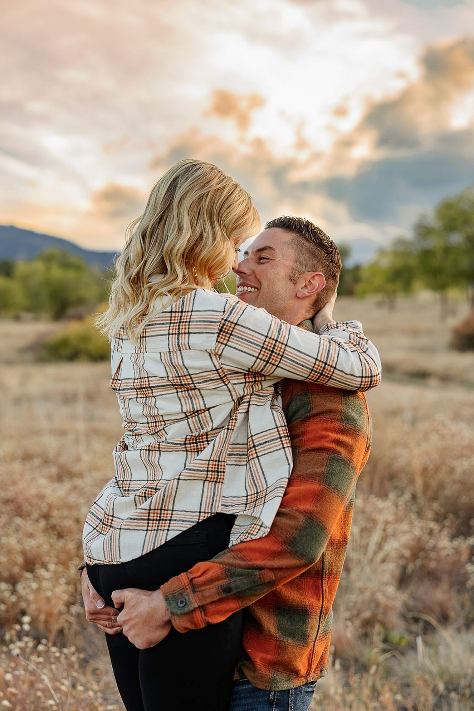 A couple portrait. The women has jumped up on the man, they are smiling at each other and he is holding her. Captured by Michelle Betz Photography