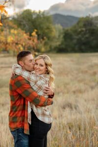 A couple hugging each other, he is kissing her on the cheek. Photo taken by a Colorado Springs engagement photographer.