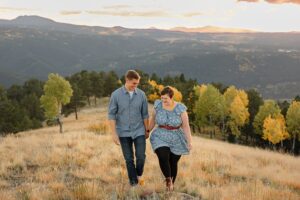 A couple holding hands and walking, smiling at each other. Captured by Colorado Springs Engagement Photographer, Michelle.