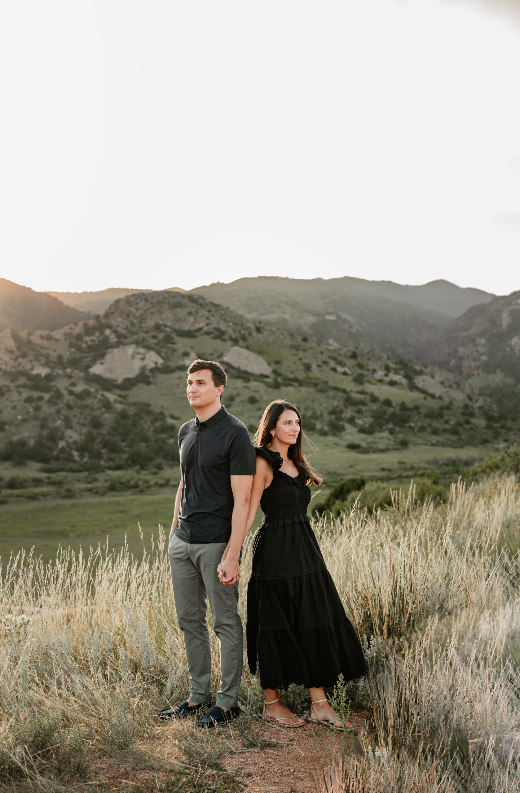 Engagement portrait in the Colorado Springs mountains. The couple is holding hands looking away from each other.