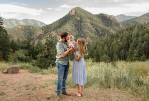 A family kissing their baby. Surrounded by the Denver mountains. Photo captured by Colorado Springs family photographer, Michelle.