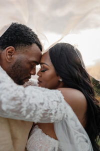 A couple holding each other under a vail. In wedding day attire. They are touching forheads and closing their eyes. In Colorado.