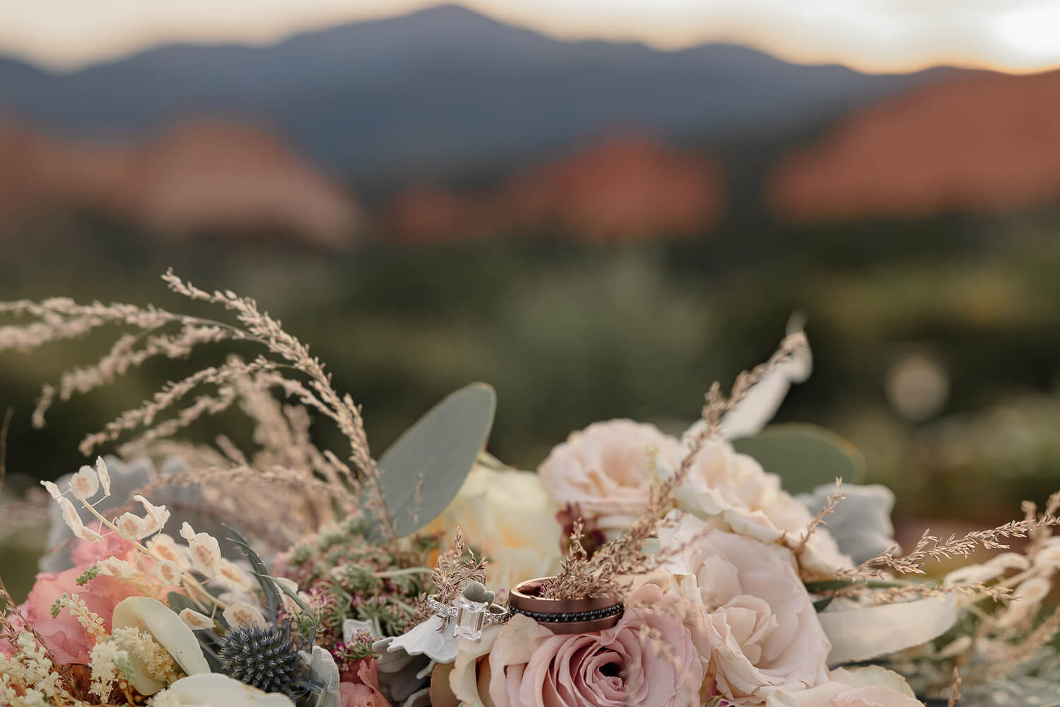 Detail shot of wedding bouquet and rings in front of the Colorado mountains