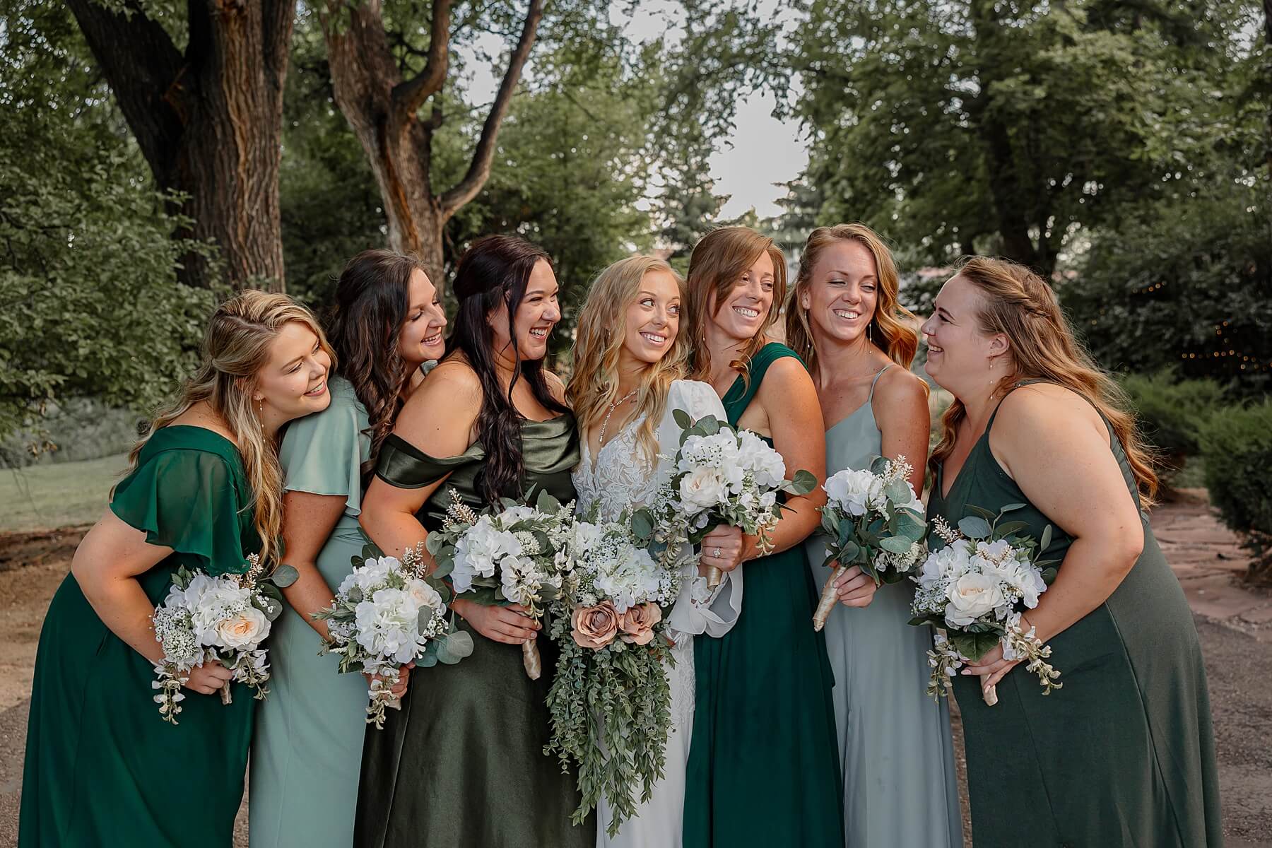 bride and bridesmaids phtoo with them all looking at each other smiling. Captured by Colorado Springs wedding photographer