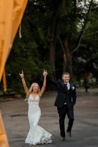 A bride and groom smiling and yelling in joy at their grand entrance. Captured by Michelle, a Colorado wedding photographer.