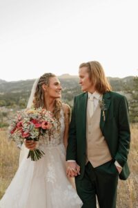 bride and groom sunset wedding photos. They are holding hands and smiling at each other. At a Colorado wedding venue.