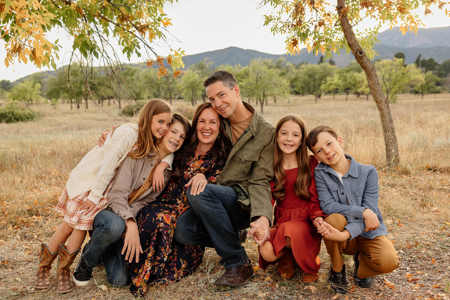 Family of four children all hugging and smiling for a portrait. Surrounded by fall in Colorado Springs. Captured by family photographer Michelle Betz Photography