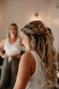 Bride smiling to the side as she gets ready with her girls. Captured by Michelle Betz Photography, a Colorado wedding photographer