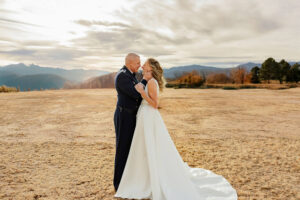 Bride and Groom portrait. The groom is grabbing her face and they are smiling at each other. Surrounded by mountains at a Colorado Boulder Wedding Venue.