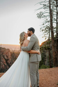 A couple kissing each other on their wedding day. In wedding attire. With Denver mountains in the background. Captured by Denver engagement photographer, Michelle Betz