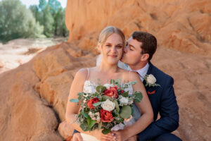 Bride and Groom Portrait at Garden of the Gods. The groom is kissing her cheek.