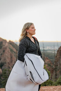 A bride on her Colorado elopement day. She is holding her wedding dress, about to get dressed in the mountains.