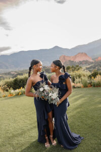 Two bridesmaid twins smiling at each other. Wearing a blue dress, and surrounded by Garden of the Gods