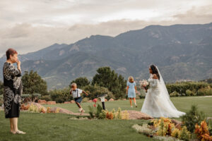 A candid photo of the bride, children, and guests. They are all walking with mountains in the background. Photo taken by Michelle, a Colorado wedding photographer. 