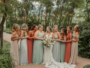 Bride and bridesmaids on wedding day, holding bouquets and smiling at each other. Photo captured by Michelle Betz, a Colorado wedding photographer.