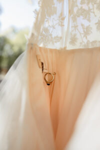 Detail wedding photo of a ring pinned to the inside of wedding dress. Captured by Michelle Betz Photography