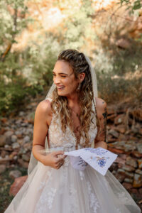 A bride, reading a letter from her father on her wedding day. She is laughing to the side. Captued at a Auora wedding venue by Mihcelle Betz Photography