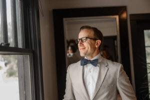 The groom on his wedding day looking out the window. Photo captured by Michelle Betz Photography