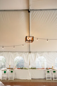 A photo of the reception site at Stone Mountain Lodge Venue. A white tent, with twinkle lights, and a large table.