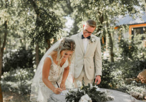 A bride and groom signing married license. Outside in a beautiful garden area. At Hillside Gardens and Event Center wedding venue. 