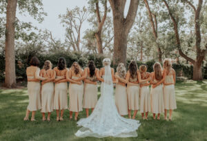 Bride and Bridesmaids looking away from the camera with their arms around each other. 