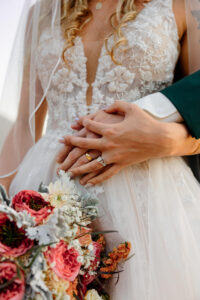 A detial shot of the bride and her bouquet, holding hands with her groom.