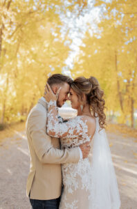 A bride and groom holding each other. Surrounded by yellow fall leaf trees. Photo taken in Estes Park, CO