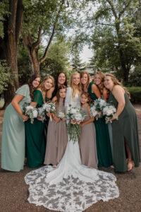 A bride and bridesmaid portrait, the bride and her girls are leaning towards each other and smiling at the camera. 