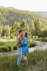 A couple engagement portrait. The man is kissing the girt on the cheek and she is smiling. Captured by Michelle Betz Photography, a Colorado Springs engagement photographer.