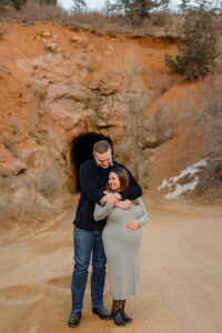 A couple holding each other for a maternity session. Taken at Gold Camp Rd in Colorado Springs