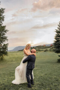 A bride and groom portrait, the groom is lifting up the bride, and they are smiling at each other. Captured by Michelle Betz Photography