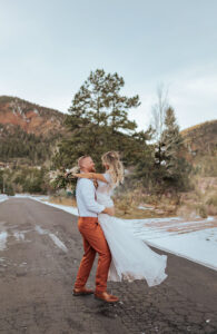 Bride and groom portrait. The groom is lifting the bride up and they are smiling at each other. Captured by Michelle Betz Photography, a Colorado wedding photographer.