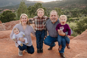 Grandparents with thier three young grandchildren. Smiling at the camera. Captured at Garden of the Gods by Michelle Betz Phototgraphy