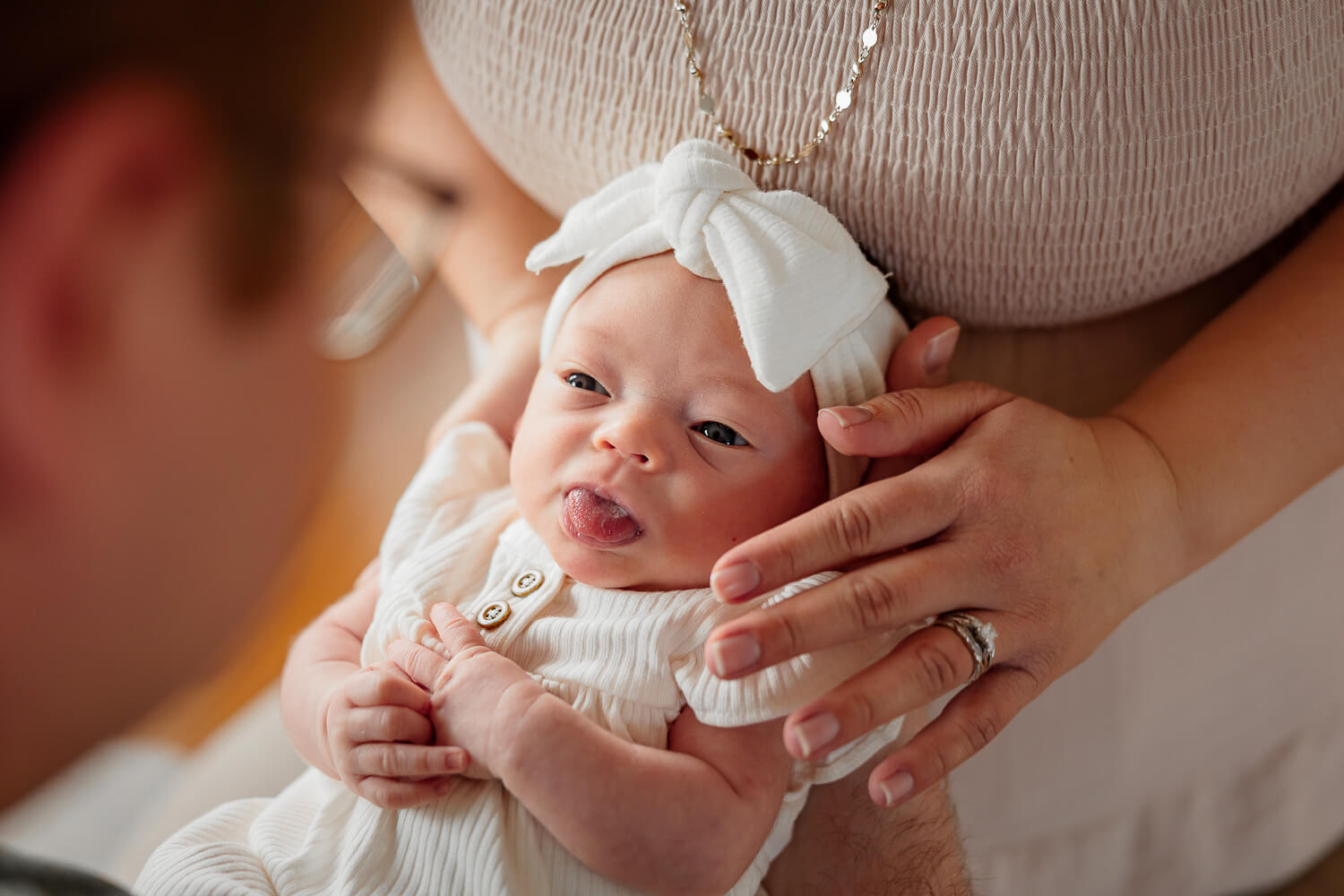 A newborn baby accidentally smiling and sticking her tongue out. Photo taken by Michelle, a Colorado Springs Newborn Photographer