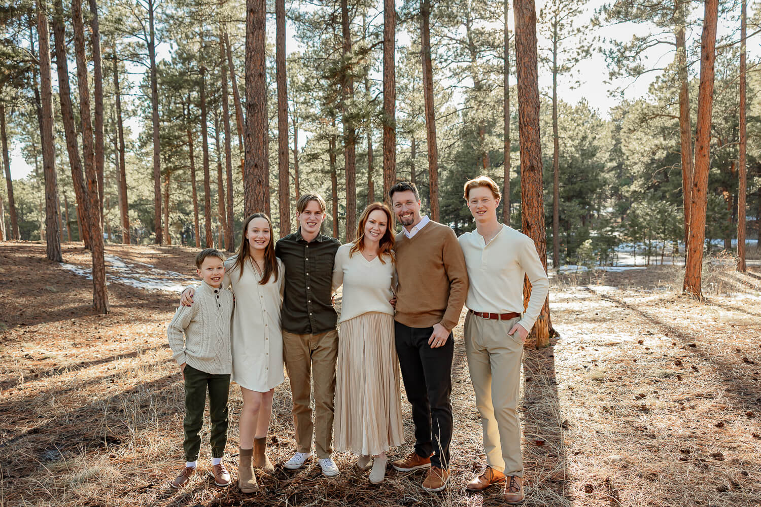 A family smiling together in the Colorado Springs Forest at Fox Run Park.